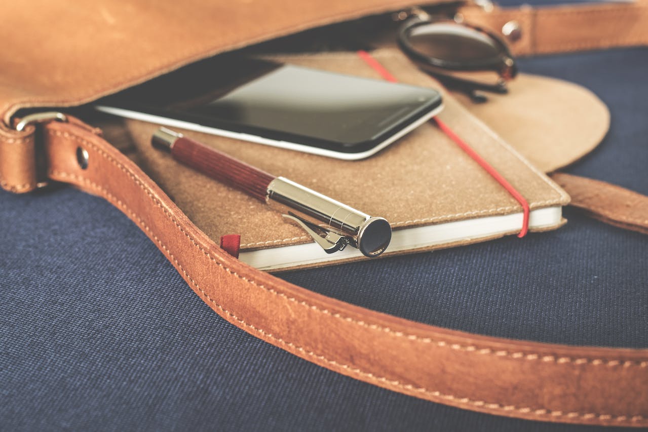 Smartphone Displaying Black Screen on Notebook Beside Pen and Sunglasses Smartphone Displaying Black Screen on Notebook Beside Pen and Sunglasses<br />
